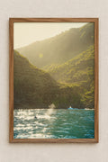 Sunlit coastline with glittering water and green cascading mountains featuring a dolphins fin jumping out to say hello
