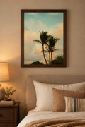 Sunset palm tree photograph without a white border in a dark wooden frame above a bed in a warm bedroom