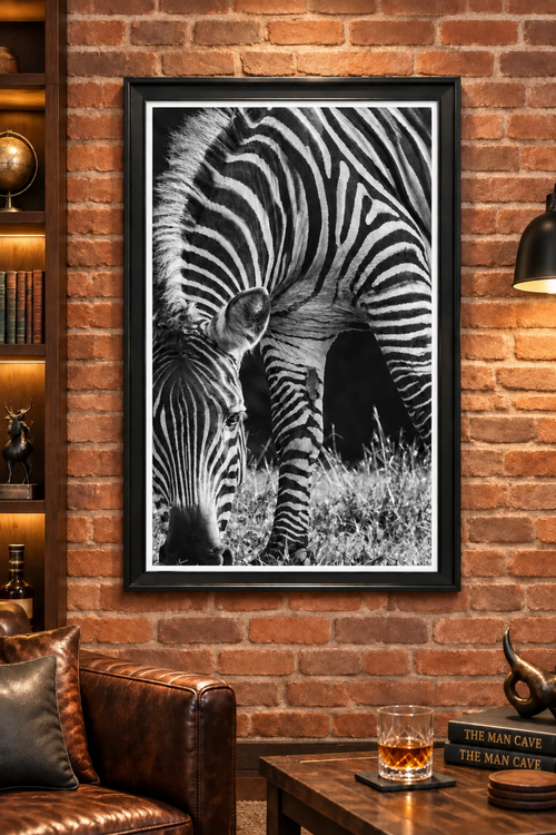 Black-and-white zebra print with a narrow white border inside a black frame on a brick wall