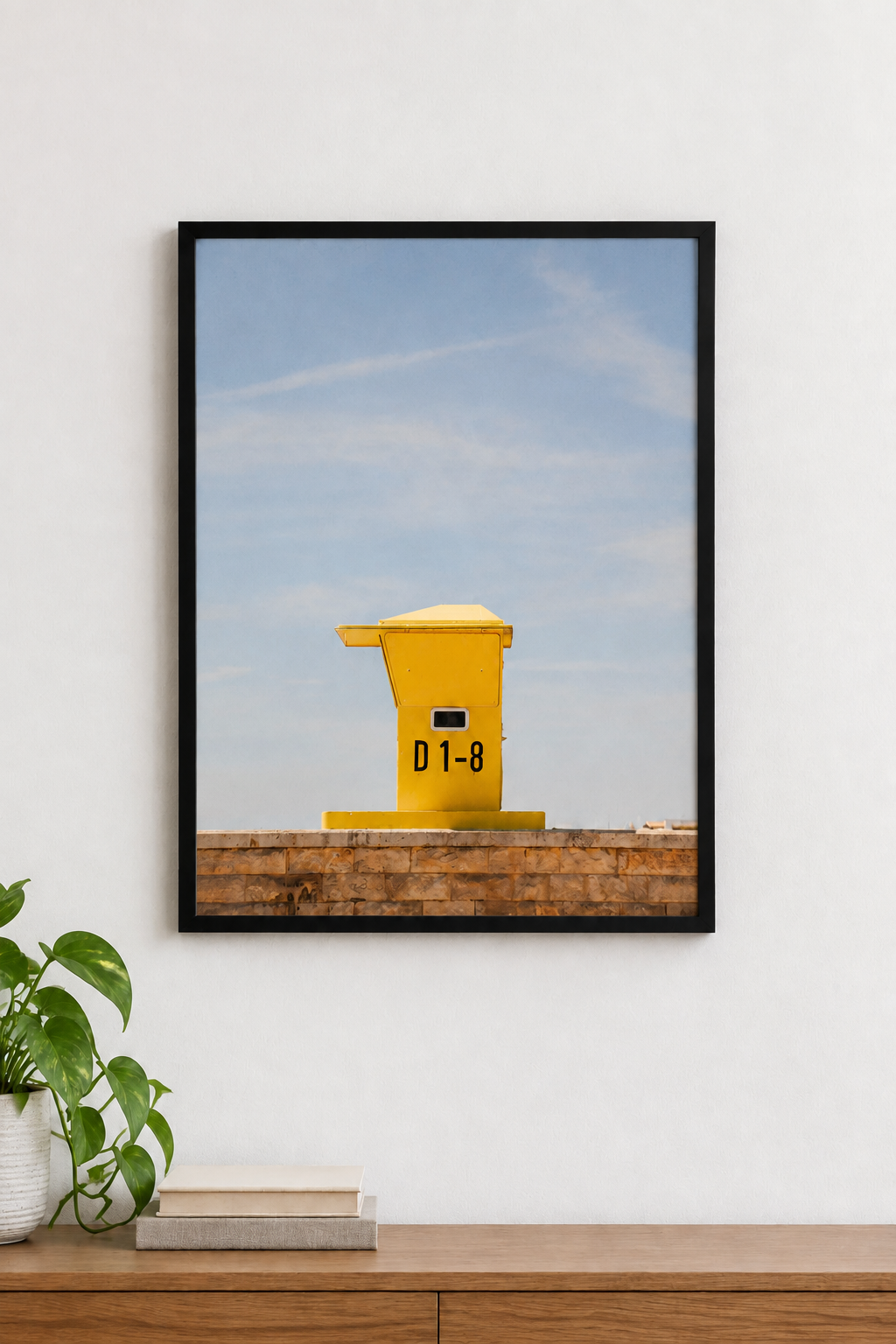 Yellow structure against a blue sky and stone wall, displayed in a black frame without a white border